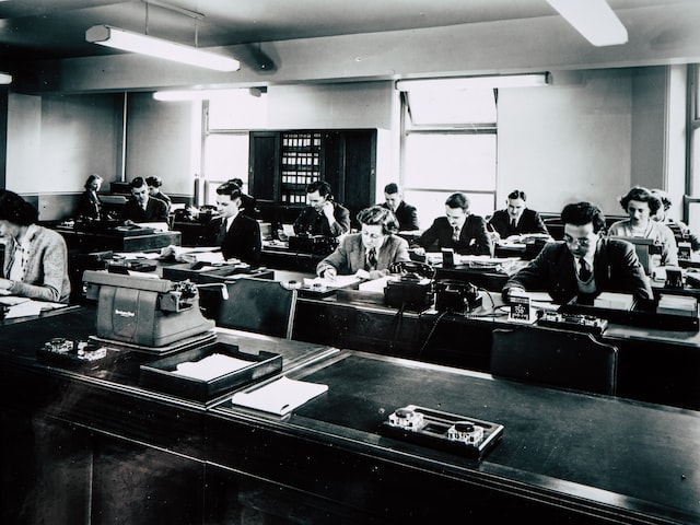 Several men sitting in their desks working in front of their typing machines. 