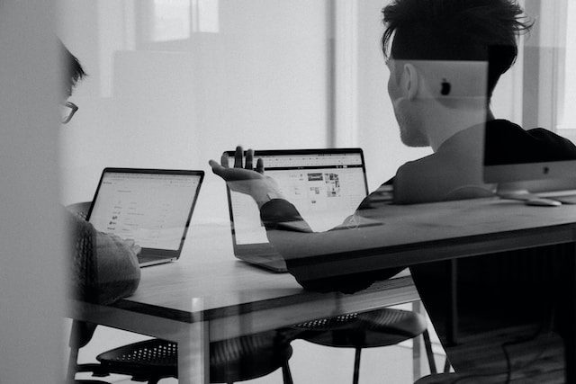 A black-and-white picture with a manager giving feedback to an employee.